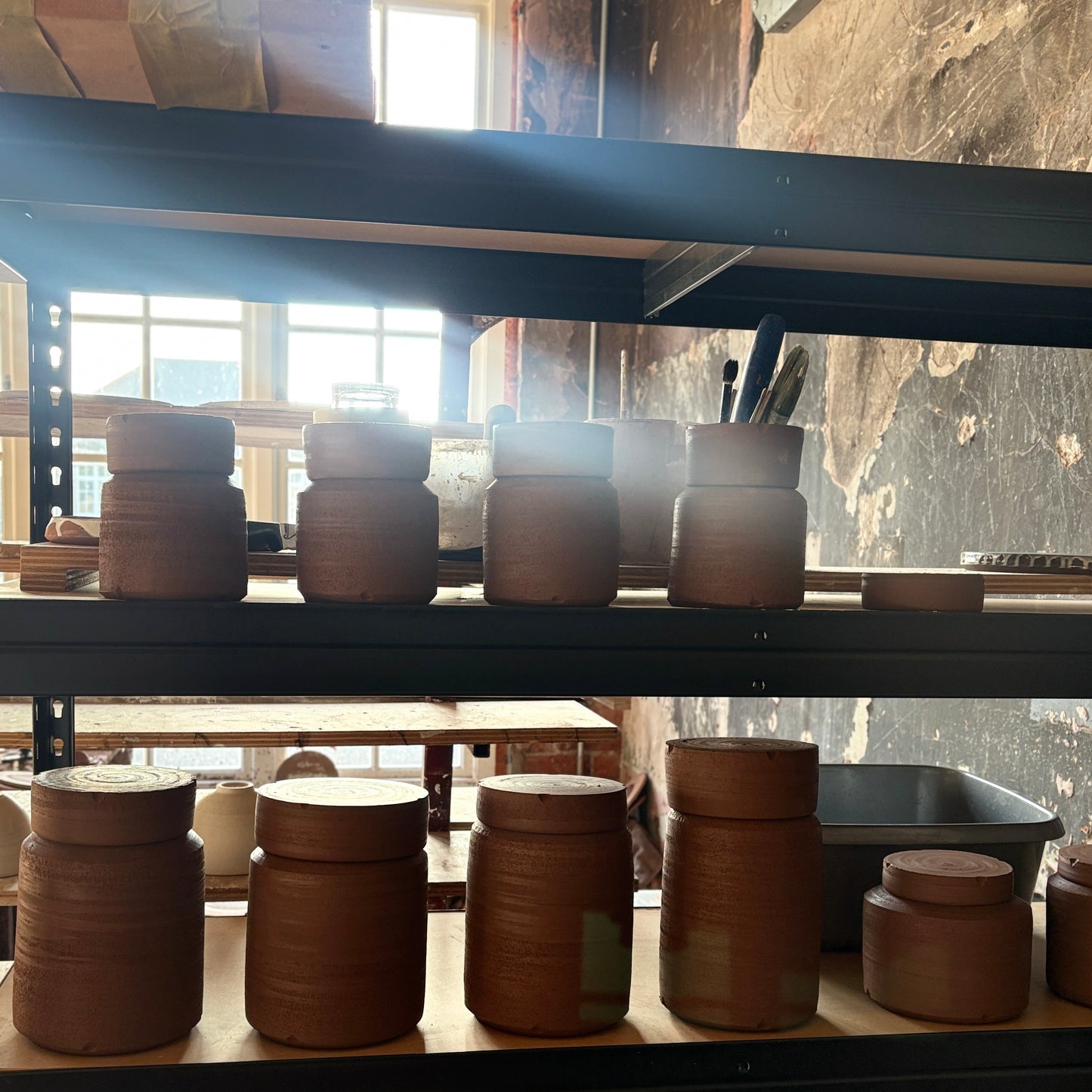 A variety of handmade ceramic Vessels for Life drying on a studio shelf before firing in Belfast